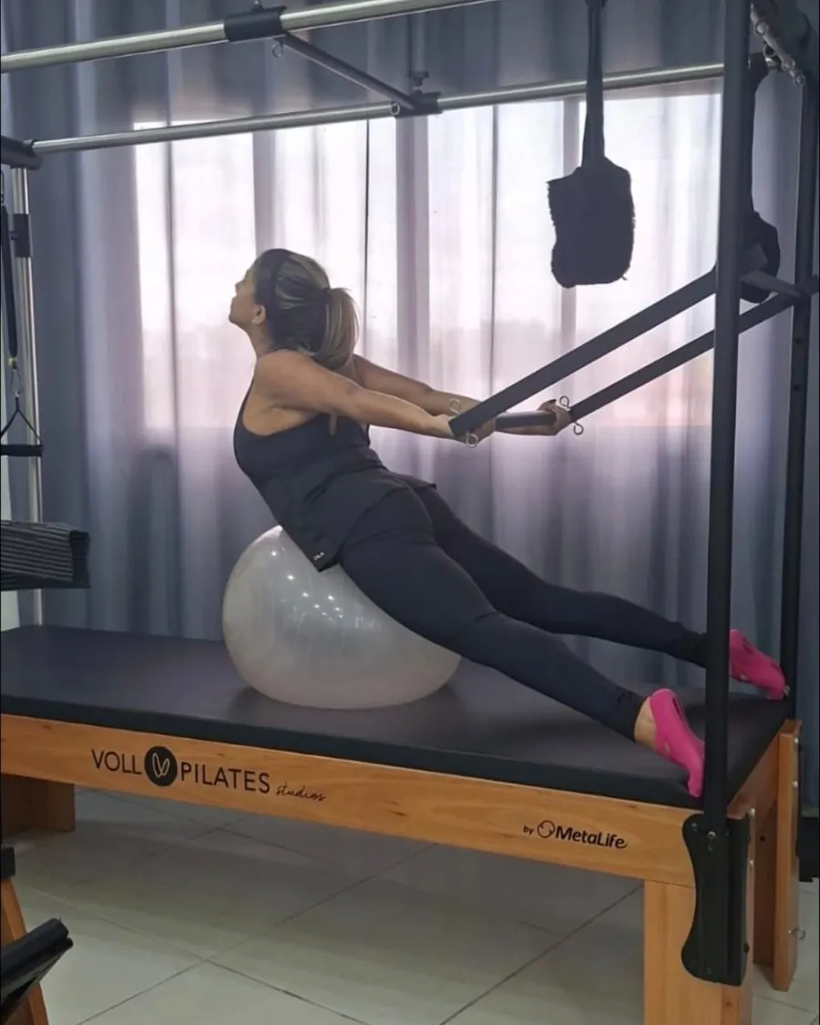 Aluna em exercício de tronco no Cadillac, apoiada na bola